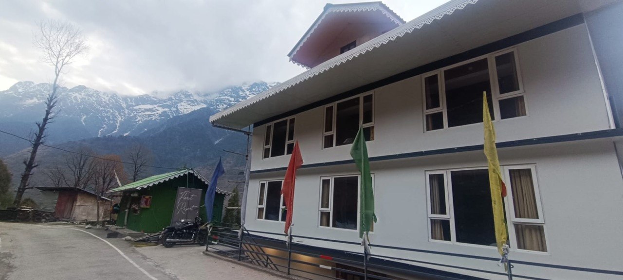The real exterior of Floret Resort beside the road in Lachung, with snowy Himalayan peaks behind it