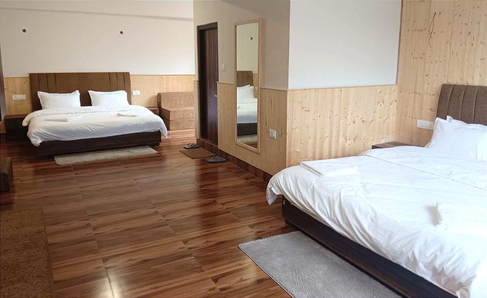Two made-up double beds facing each other across the family room, with a sofa between them