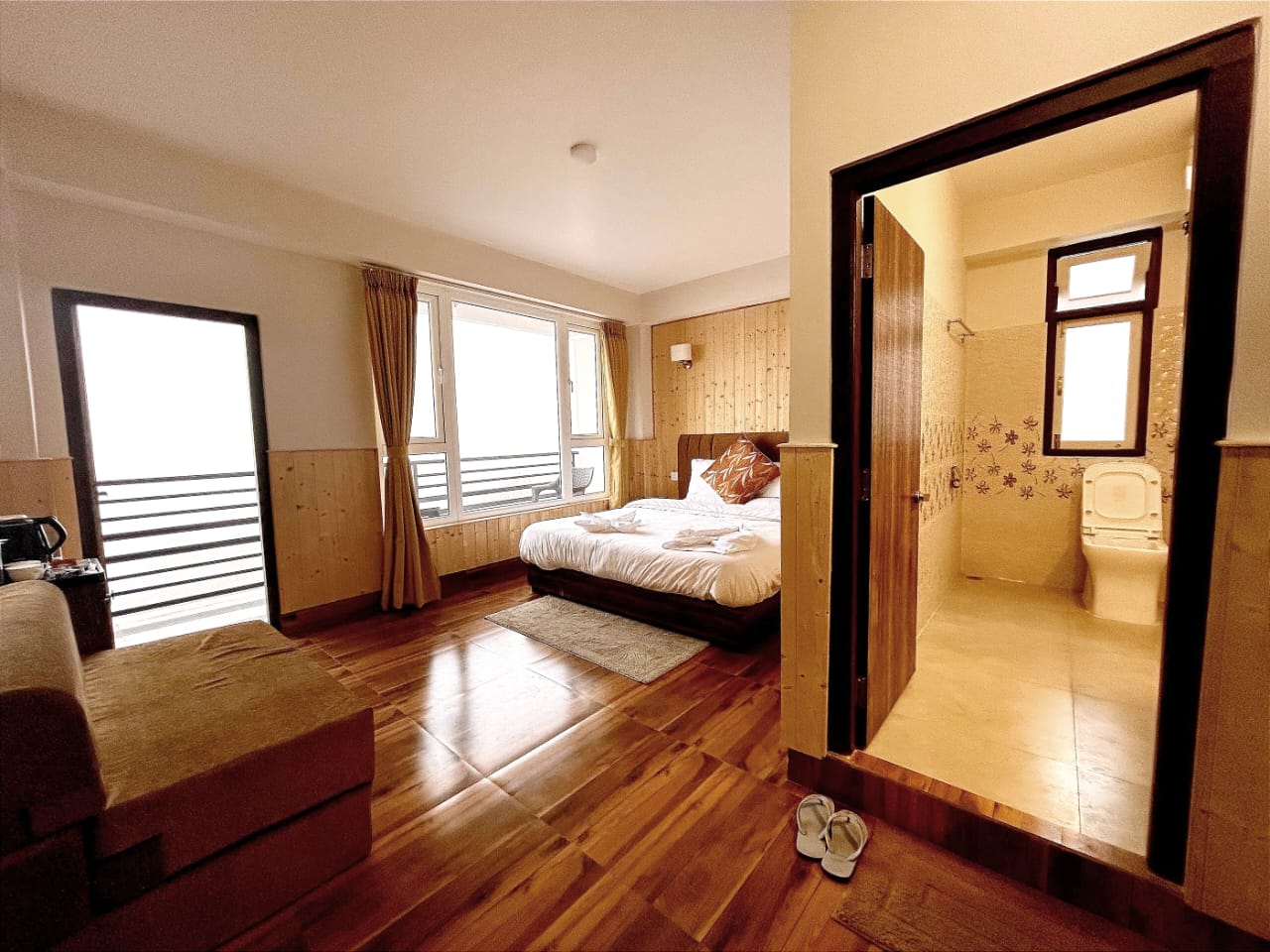 Mountain view room with a double bed, a balcony door on one side and an attached tiled bathroom on the other