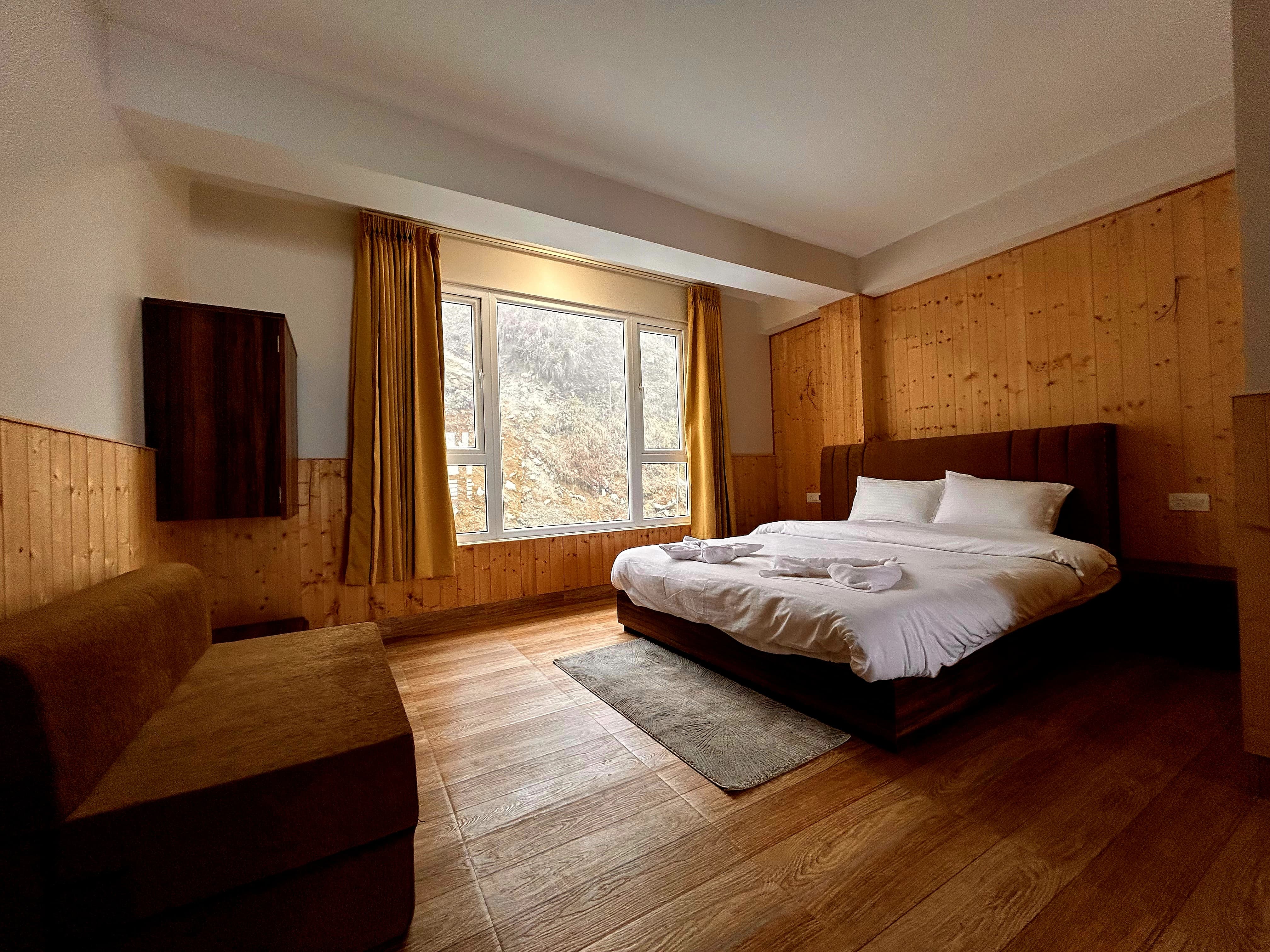 Forest view room with a double bed and a window looking onto the wooded hillside behind the property