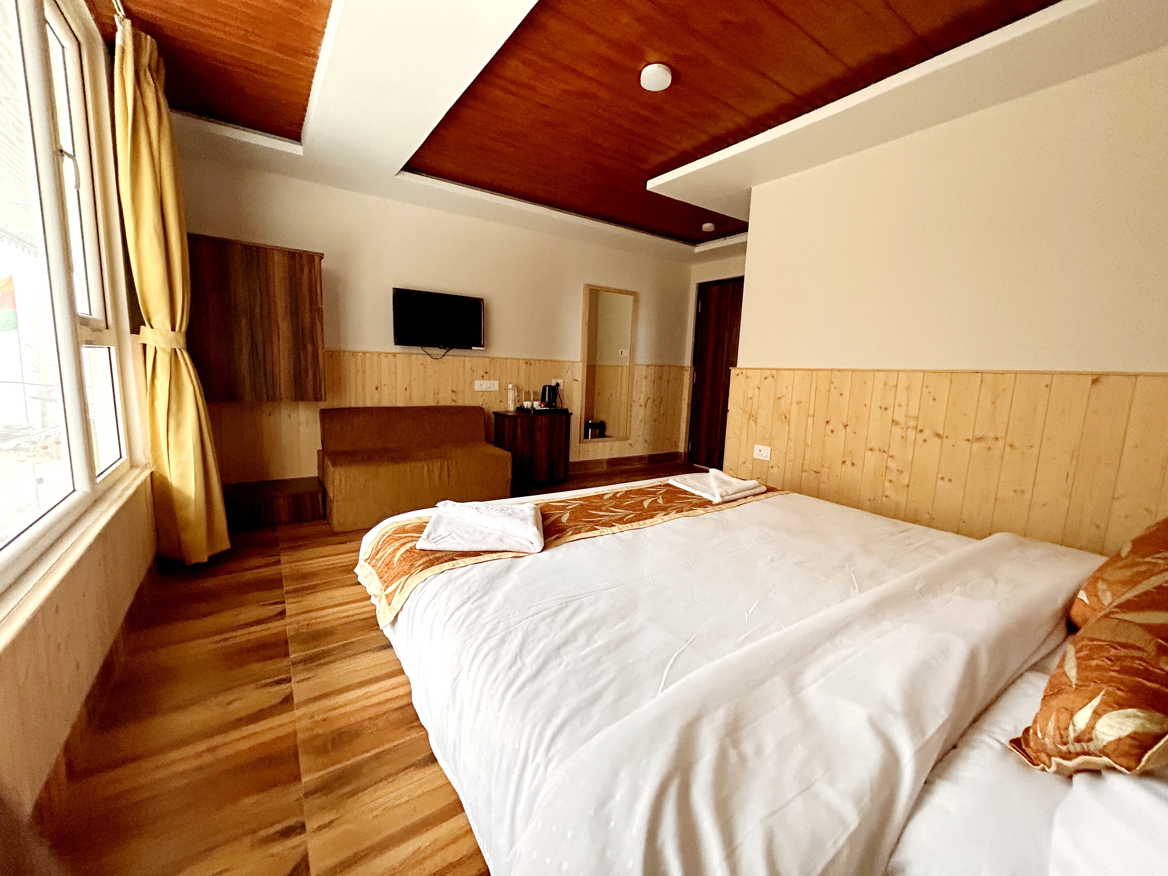 Forest view room with a wooden ceiling, wall-mounted television, wardrobe and sofa